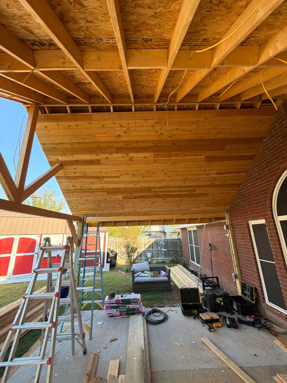 Patio roof ceiling and timber supports beside a brick house